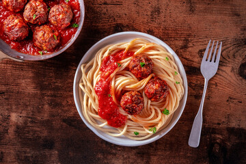 Meatballs. Beef meat balls, overhead flat lay shot in a pan and with a plate of spaghetti pasta, on a rustic wooden background