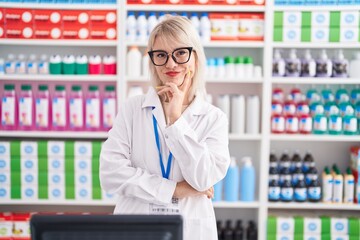 Young caucasian woman working at pharmacy drugstore looking confident at the camera smiling with...