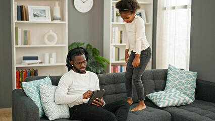 African american father and daughter sitting on sofa working while child disturb at home