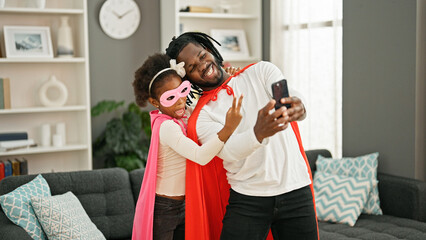 African american father and daughter smiling confident wearing superhero costume make selfie by smartphone at home © Krakenimages.com