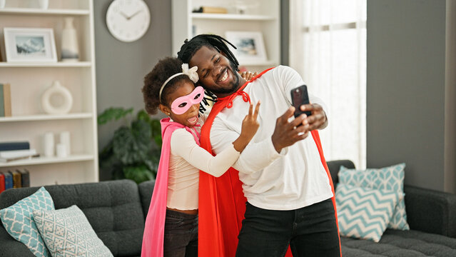 African american father and daughter smiling confident wearing superhero costume make selfie by smartphone at home