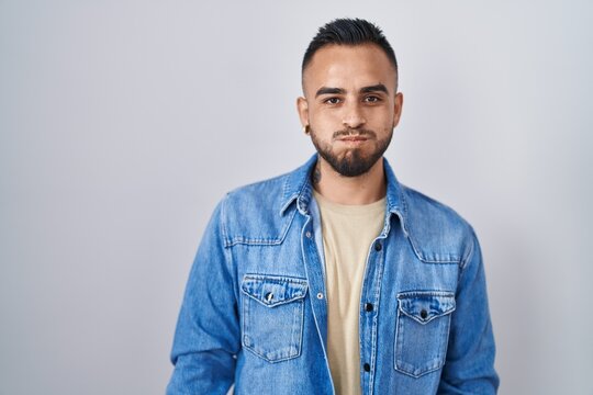 Young hispanic man standing over isolated background puffing cheeks with funny face. mouth inflated with air, crazy expression.