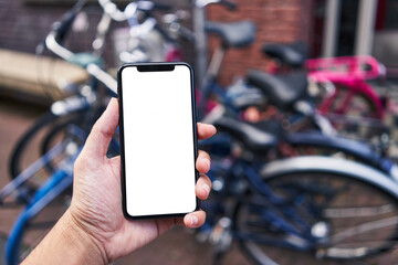 Man holding smartphone showing white blank screen at bike parking