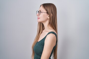 Young caucasian woman standing over white background looking to side, relax profile pose with natural face and confident smile.