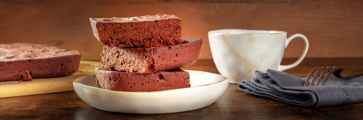 Chocolate brownie with tea, simple coffee cake, a side view panorama on a dark rustic wooden background