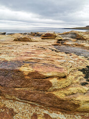 The shore of red stones next to the rocks are Two Brothers on the Fishing Peninsula. The picturesque shore of the harsh Barents Sea. The North of Russia. The Kola Peninsula. The Arctic