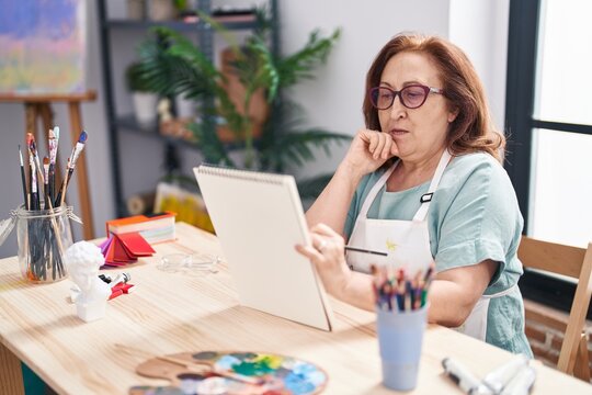 Senior woman artist drawing on notebook at art studio