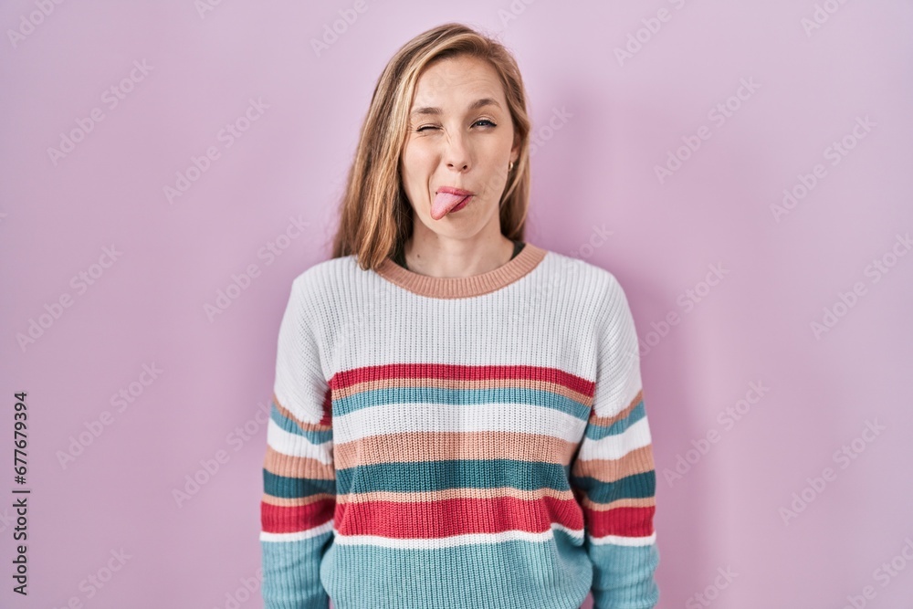 Sticker Young blonde woman standing over pink background sticking tongue out happy with funny expression. emotion concept.