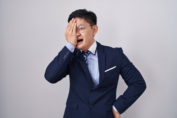 Young asian man wearing business suit and tie yawning tired covering half face, eye and mouth with hand. face hurts in pain.