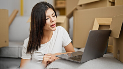 Young caucasian woman using laptop sitting on floor at new home