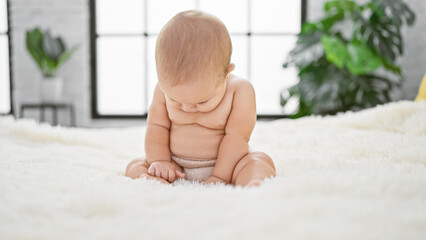 Adorable infant, a little serious, waking up in the comfort of home, sitting shirtless on a cozy...