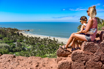 Fototapeta na wymiar A girl with a child on the background of the view from Forte Chapora. In the background is a view of the beaches of Anjuna and Vagator in the northern part of Goa. India. Indian Ocean.