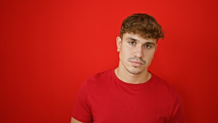 Obraz premium Young hispanic man standing with serious expression over isolated red background