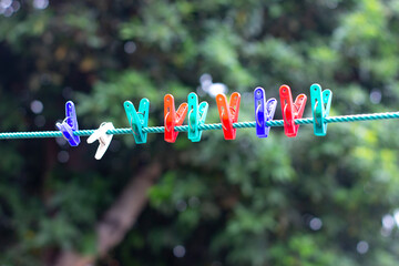 Photo of a row of colorful plastic clothespin on a green plastic rope during the day