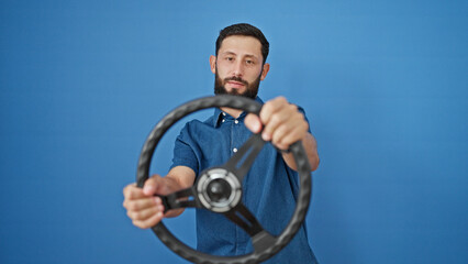 Fototapeta na wymiar Young hispanic man using steering wheel as a driver over isolated blue background