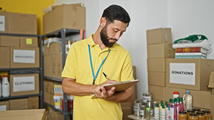 Young hispanic man volunteer writing on document at charity center