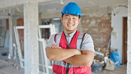  builder smiling confident standing with arms crossed gesture at construction site