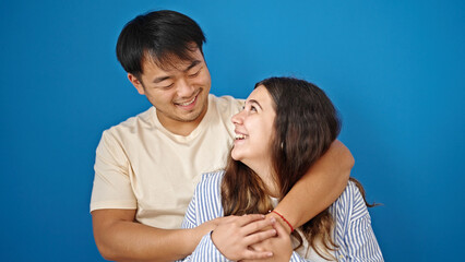 Man and woman couple smiling confident hugging each other over isolated blue background