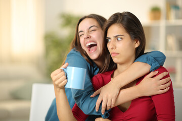 Excited woman embracing a perplexed friend - obrazy, fototapety, plakaty