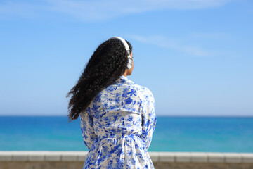 Black woman listening to music contemplating ocean