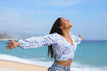 Happy black female outstretching arms on the beach