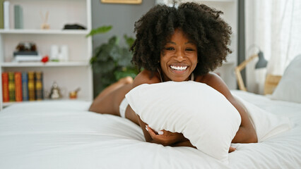 African american woman hugging pillow lying on bed looking sexy at bedroom