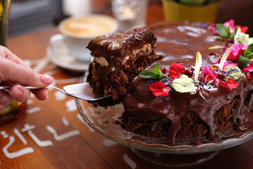 Taking a piece of chocolate cake with chocolate glaze, selective focus, close-up, with blurred background