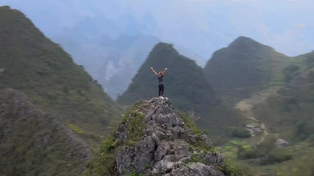 Young traveler standing on top of a mountain peak in Ha Giang Loop and enjoying the view of Vietnamese nature, centered