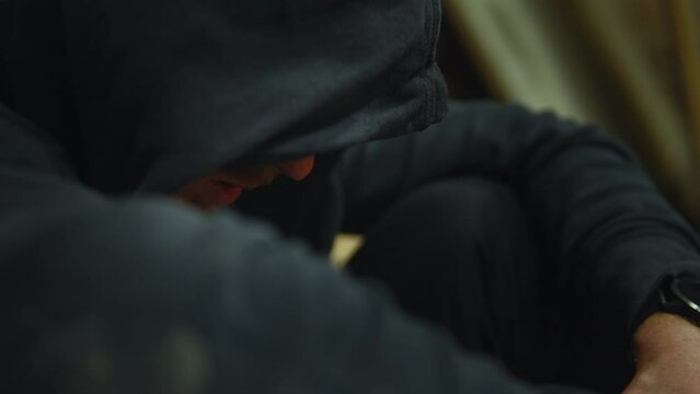 Lonely person wearing hoodie, sitting head down depressed and sad