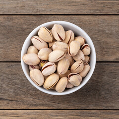 Salted roasted pistachios on a bowl over wooden table