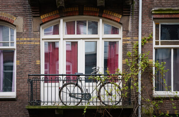 Fototapeta na wymiar Old Dutch bicycle on the balcony of a residential building in Amsterdam. Traditional urban transport in Netherlands