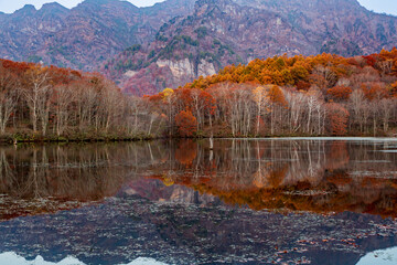 鏡池に映る朝日を浴びる紅葉の戸隠連山