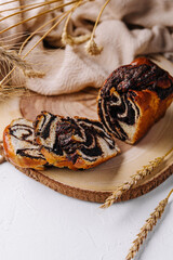 Wooden board with tasty cut poppy seed bun