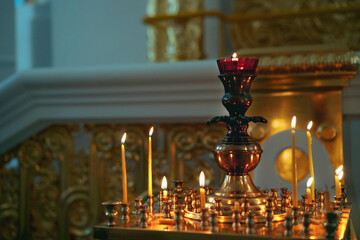 burning wax candles in a gilded candlestick in orthodox cathedral
