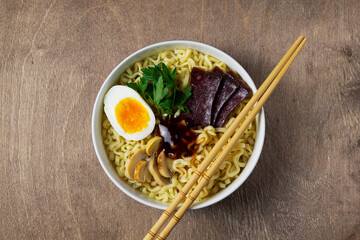 chicken noodle soup. Traditional Asian cuisine. A white bowl of Korean soup with food sticks. ramen noodles with chicken, boiled egg, mushrooms, spring onions and soy sauce. top view. copy space