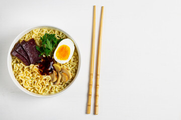 noodles with chopsticks.Japanese ramen noodles with chicken, boiled egg, mushrooms, spring onions and soy sauce. A bowl of Korean soup with food sticks. Traditional Asian cuisine. copy space. top view