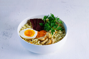 A bowl of Korean soup with mushrooms and green onions. Asian noodle soup, ramen with meat, vegetables and eggs in white bowl on the white background. Copy space.