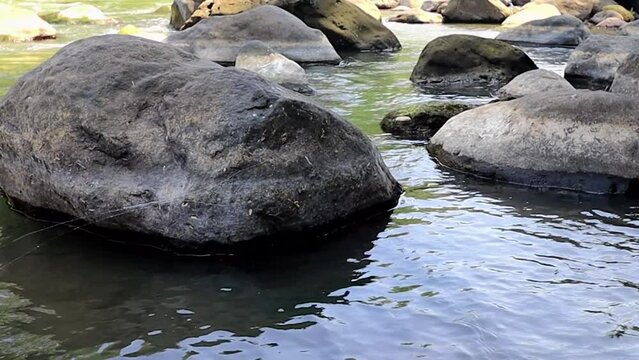 river water discharge in the dry season and black rocks scattered around