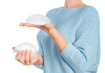 Woman holding and squeezing round implants on white background with clipping path. Mammoplasty and plastic surgery. - obrazy, fototapety, plakaty