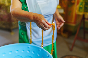 Woman lighting candles on a Baptismal font in the Orthodox Church. 