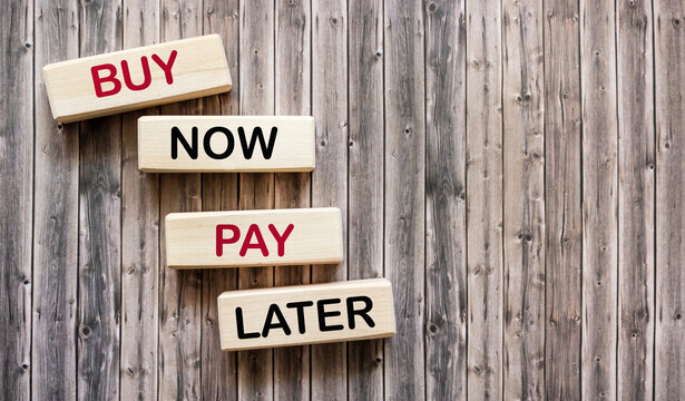 On a wooden background are four wooden blocks with the words BUY NOW, PAY LATER.