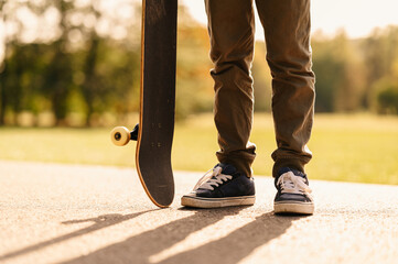 Close up photo of shoes and skateboard in park during sunset time.