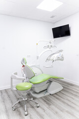 Vertical photo of a green and white dentist's room. Dental team in dental office in new modern dental room. Dental chair background and accessories used by dentists in green.