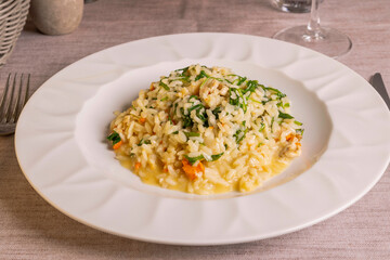 Risotto con capesante, rucola e vodka servito come primo piatto in un ristorante elegante