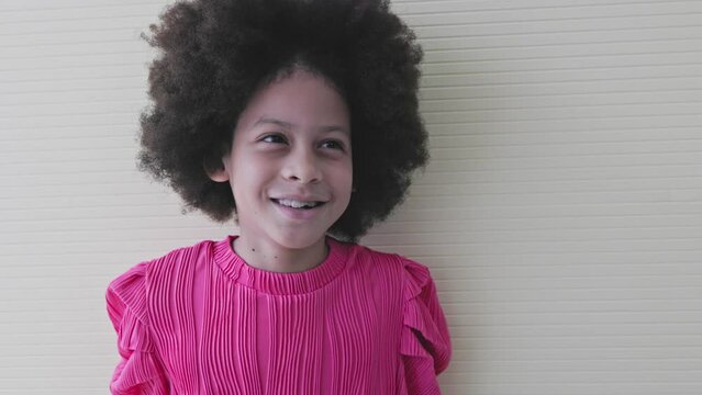 portrait of ittle girl with afro hair look at the camera giving thumbs up