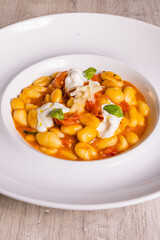 Piatto di gnocchi con pomodori, burrata pugliese, basilico e formaggio grattugiato servito come primo piatto in un ristorante