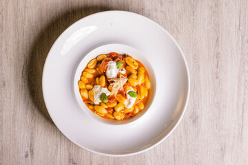 Piatto di gnocchi con pomodori, burrata pugliese, basilico e formaggio grattugiato servito come primo piatto in un ristorante