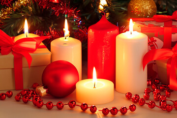 Christmas decoration with gift boxes, red candles, Christmas tree and colorful balls.