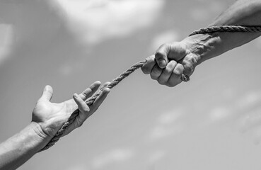 Rope, cord. Hand holding a rope, climbing rope, strength and determination. Rescue, help, helping gesture or hands. Black and white - obrazy, fototapety, plakaty