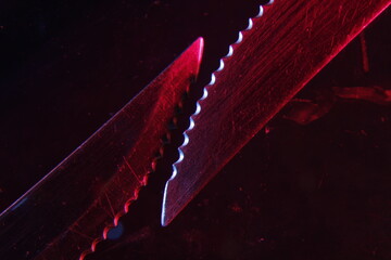 Cuchillo dentado de metal con dientes muy afilados, se utiliza para cortar y rebanar sin hacer fuerza, con luz roja-azulada forma un diseño original abstracto con fondo negro